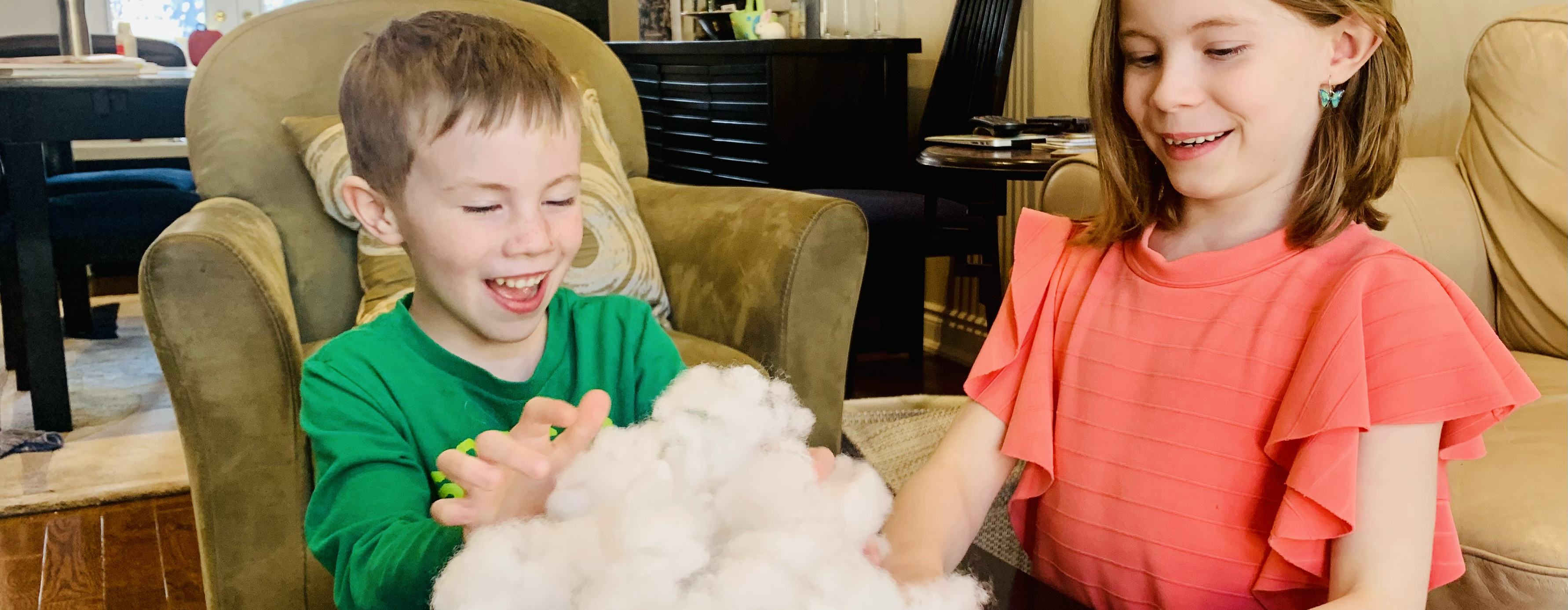 Two young children playing with cotton on a coffee table in a living room